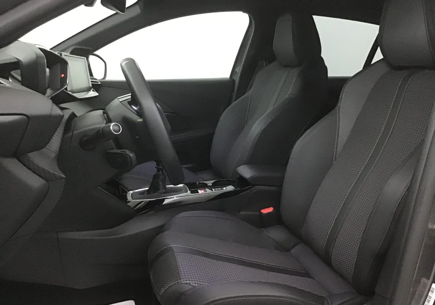 Vue intérieure côté conducteur de la Peugeot 208 1.2 PureTech 100 GT S&S avec sièges en cuir noir et volant cuir.