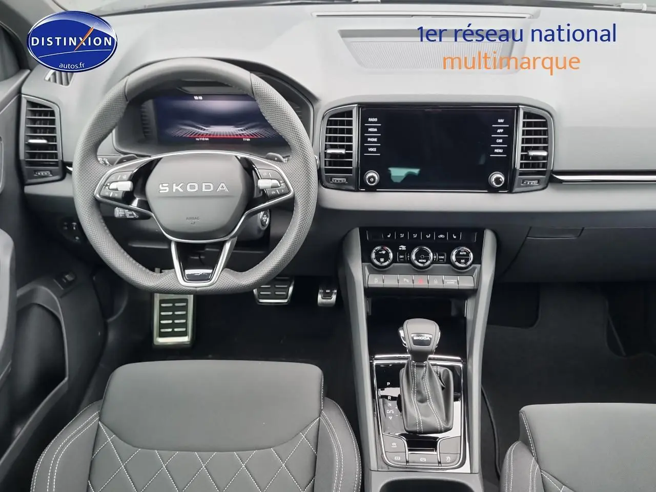 Intérieur du Skoda Karoq 2025 noir, vue frontale du poste de conduite avec volant sport et écran tactile central.