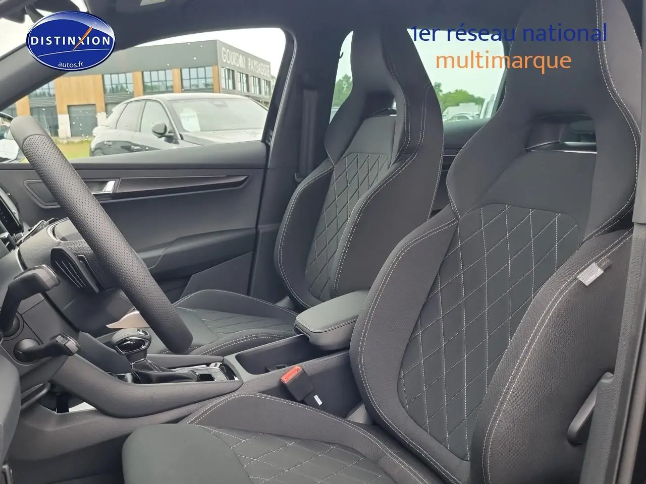 Intérieur avant du Skoda Karoq noir 2025, sièges sport avec surpiqûres contrastées et accoudoir central visible.