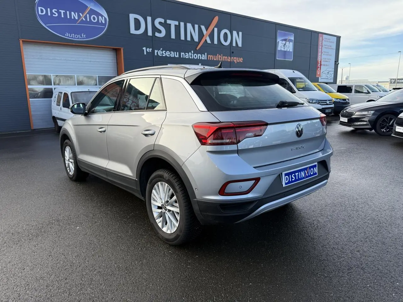 Volkswagen T-Roc gris pyrite vue 3/4 arrière droit sur parking devant concession multimarque