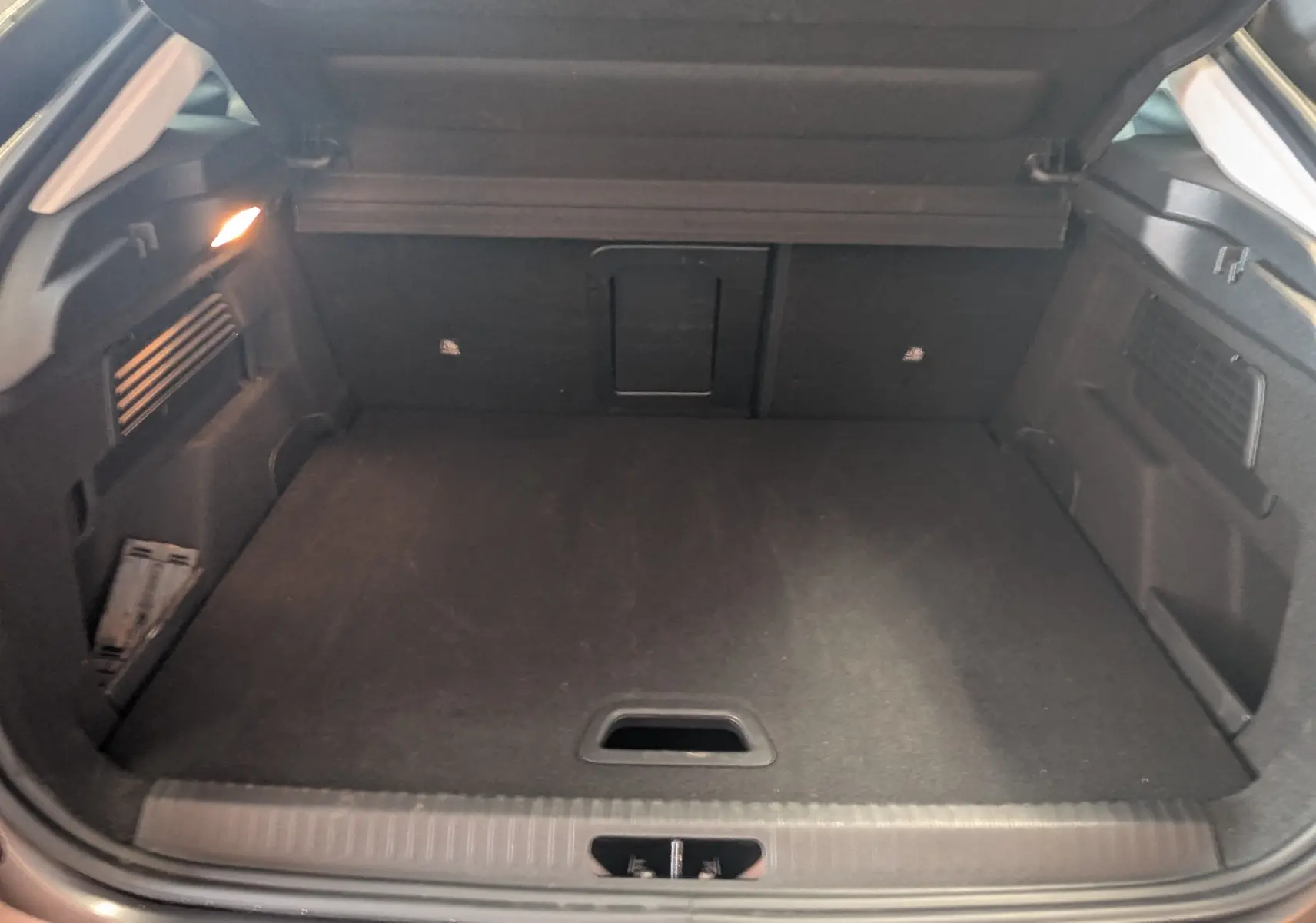 Coffre ouvert d'une Citroën C4 gris platinium, vue intérieure montrant un espace de chargement propre et éclairé.