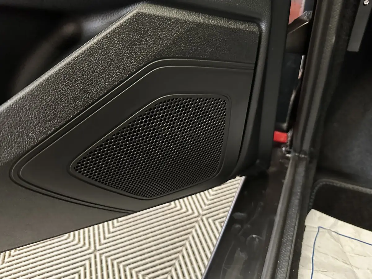 Gros plan sur la porte intérieure noire côté conducteur de l'AIXAM Ambition rouge, avec haut-parleur intégré visible.