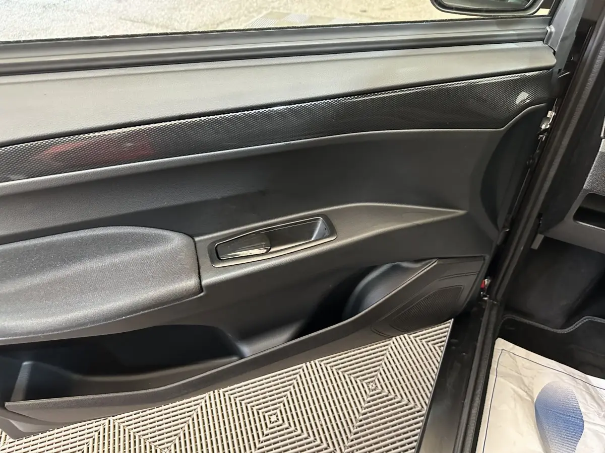 Vue intérieure du panneau de porte côté conducteur d'une Aixam Ambition rouge, avec poignée argentée et finition noire.