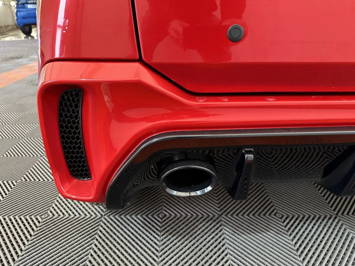 Gros plan sur l’échappement et le diffuseur arrière noir d’une Aixam Ambition rouge, vue arrière côté droit.
