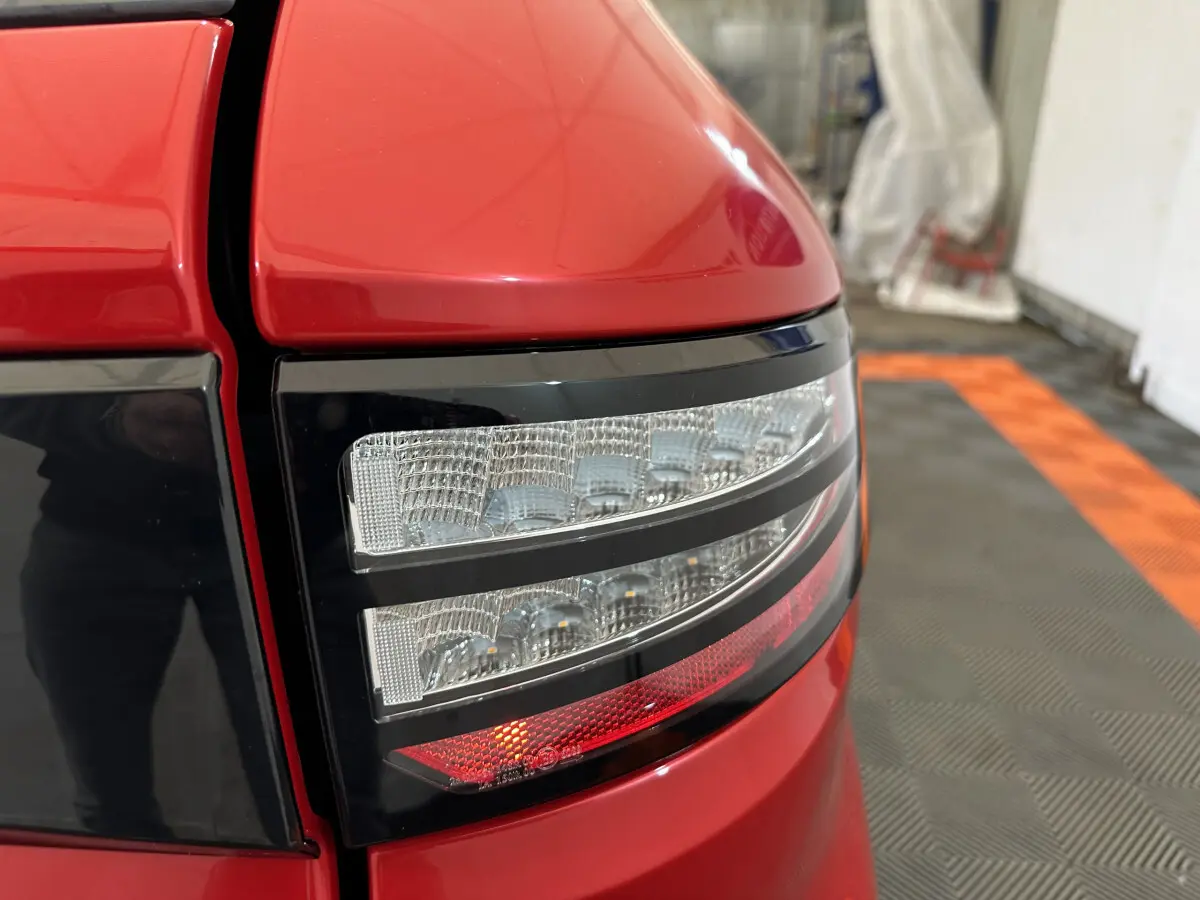 Gros plan sur le feu arrière droit rouge de l'AIXAM AMBITION 0.5 CITY COUPE GTI E5+ 2026 dans un garage.