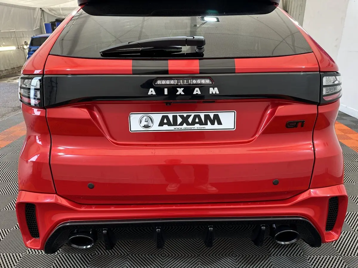 Vue arrière d'une Aixam Ambition rouge 2026 avec bande noire, logo AIXAM et double sortie d'échappement GTI.