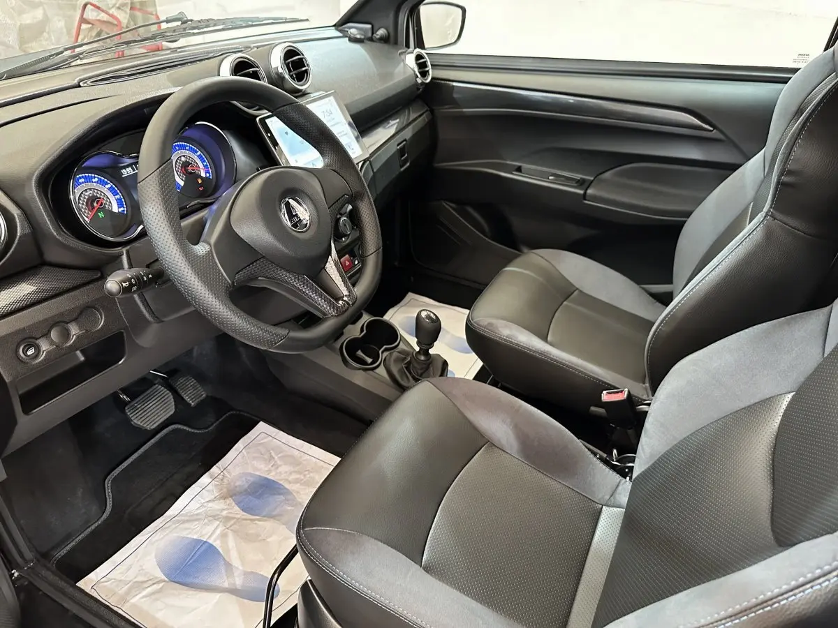 Vue intérieure côté conducteur de l'AIXAM Ambition 2026, montrant le volant, tableau de bord et sièges noirs et gris.