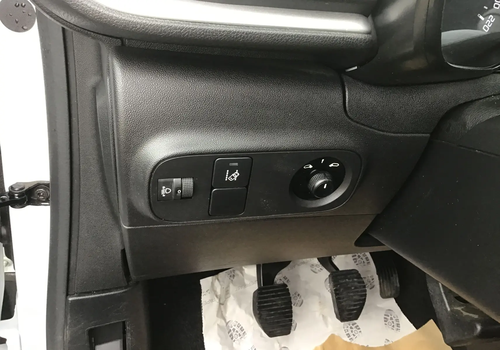 Vue intérieure côté conducteur d'une Citroën C3 blanche 2021, montrant les commandes d'éclairage et les pédales de boîte manuelle.