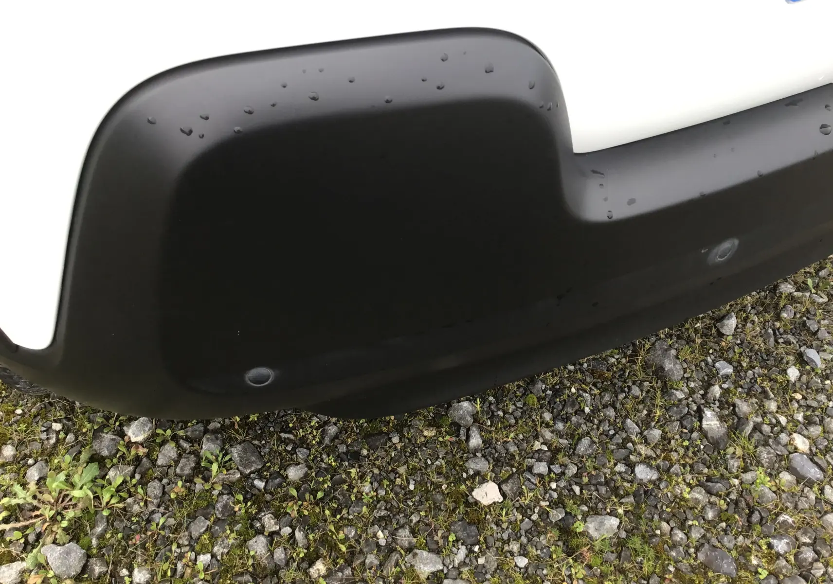 Gros plan sur le pare-chocs avant noir et blanc d'une Citroën C3 1.2 PureTech 83 Live, avec capteurs de stationnement visibles.