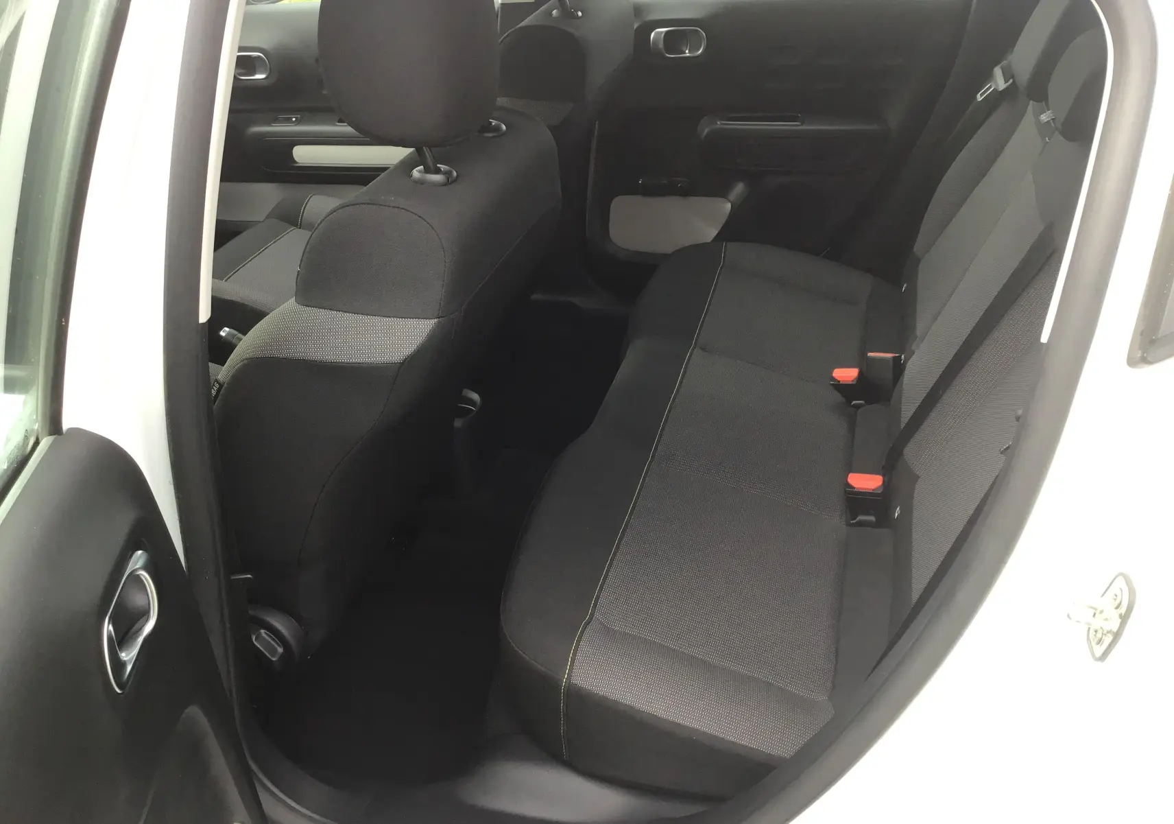 Vue intérieure arrière côté gauche d'une Citroën C3 blanche 2021, montrant les sièges arrière en tissu noir avec surpiqûres contrastantes.