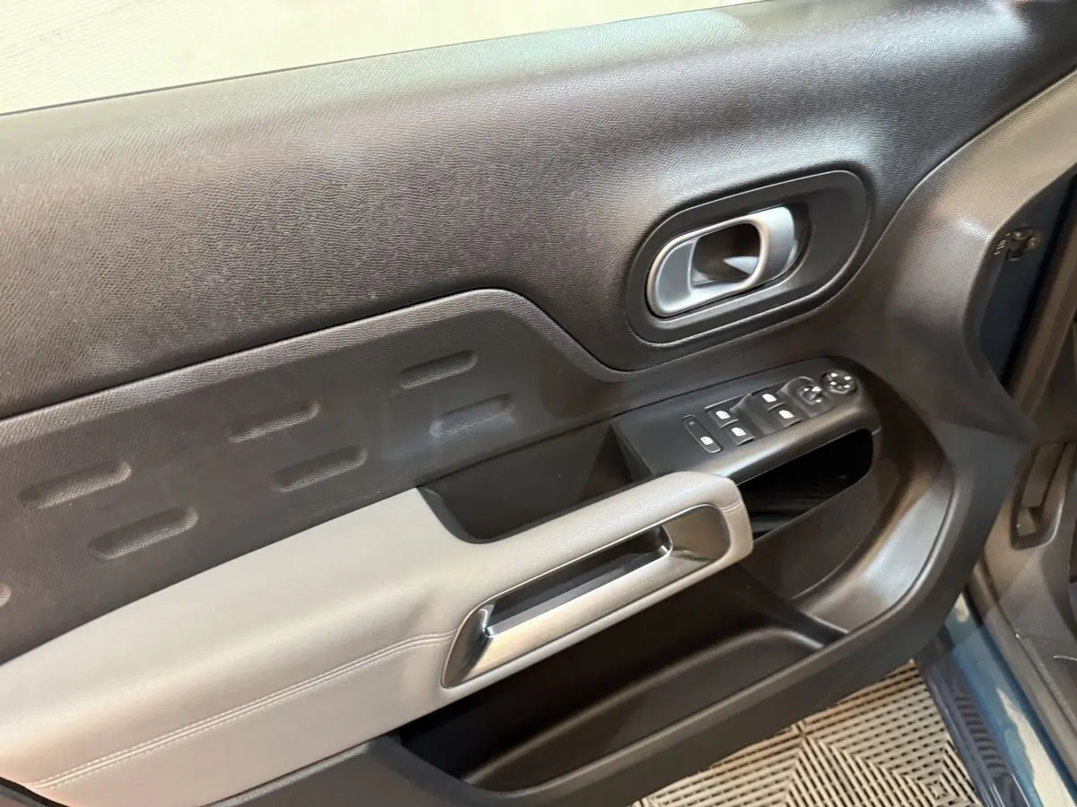 Détail de la porte avant gauche du Citroën C5 Aircross Hybrid bleu, avec commandes électriques et poignée argentée.