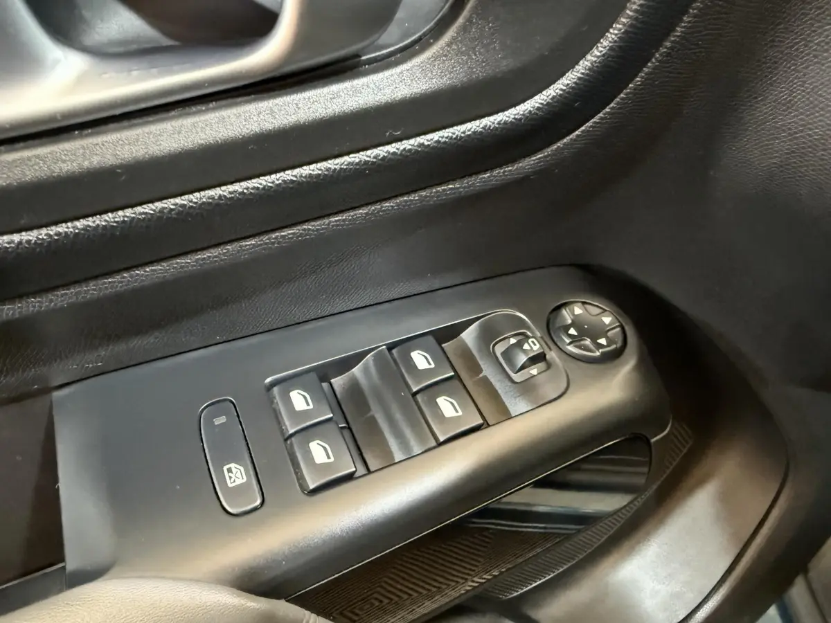 Gros plan sur les commandes de lève-vitres et rétroviseurs électriques côté conducteur d’un Citroën C5 Aircross Hybrid bleu.