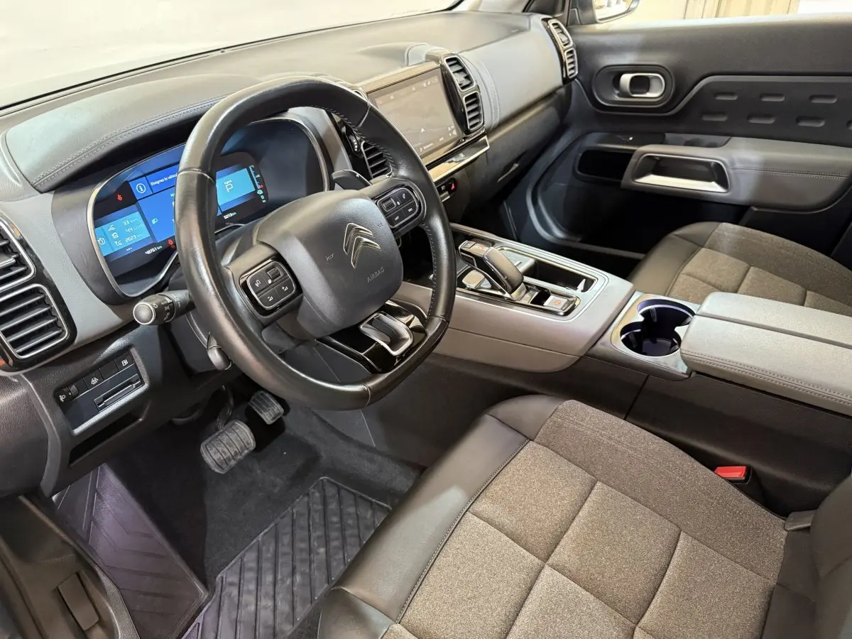 Vue intérieure côté conducteur du Citroën C5 Aircross Hybrid 225 avec tableau de bord numérique et sellerie grise.