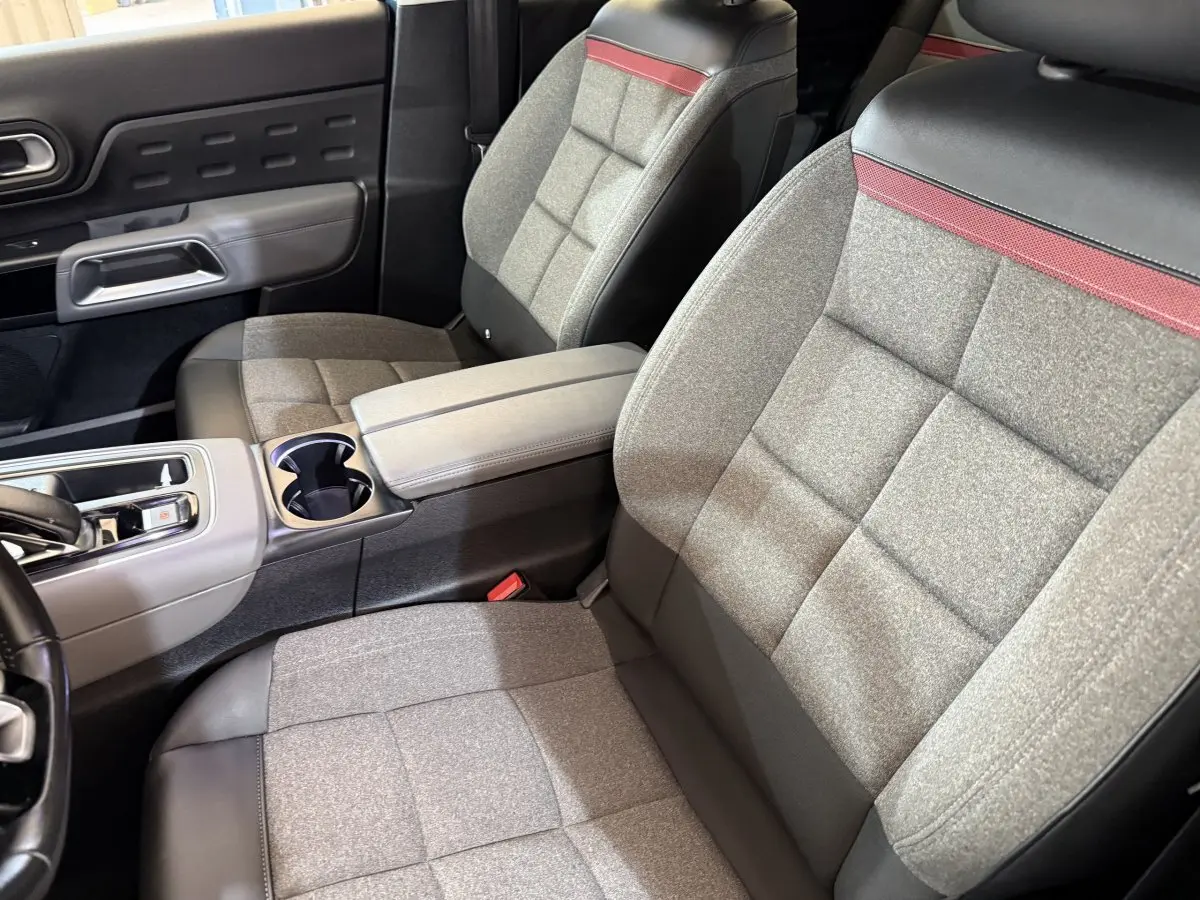 Vue intérieure côté avant droit du Citroën C5 Aircross Hybrid avec sièges tissu gris et cuir noir, bande rouge décorative.