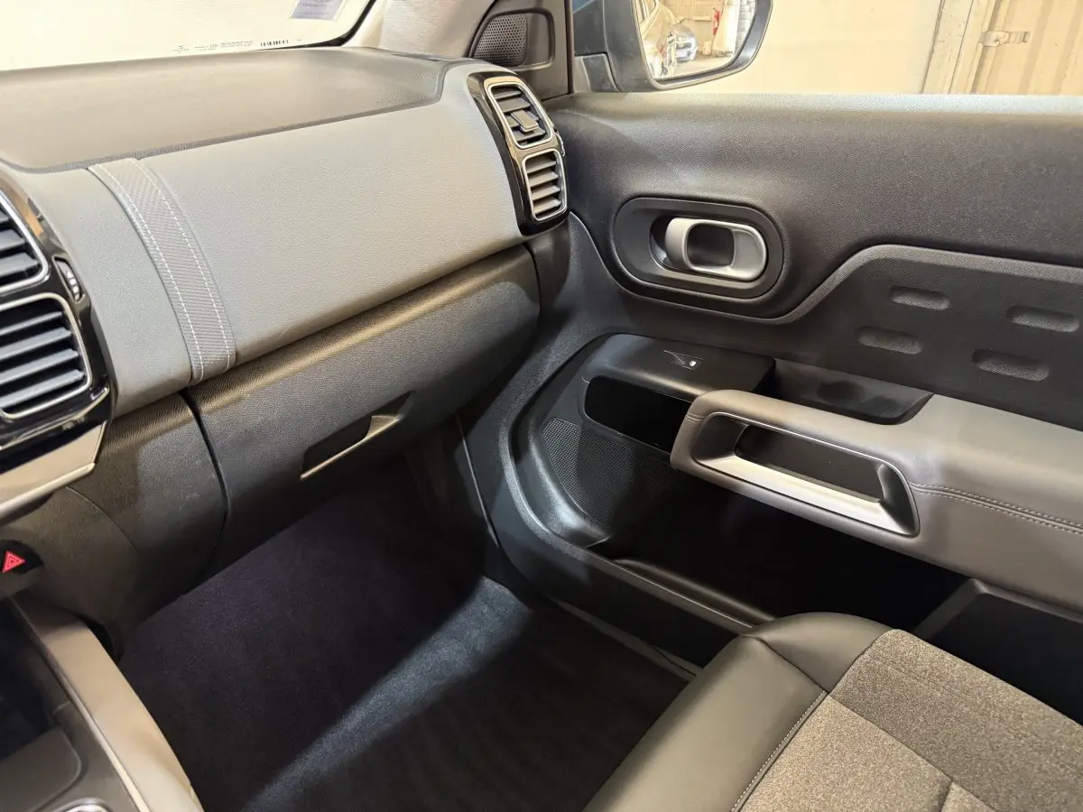 Vue intérieure côté passager du tableau de bord et de la porte du Citroën C5 Aircross Hybrid bleu, avec garnitures grises et noires.