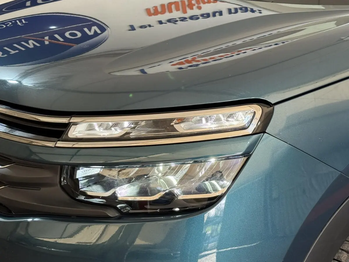 Gros plan sur le phare avant droit du Citroën C5 Aircross Hybrid bleu, mettant en valeur ses feux LED et la calandre chromée.
