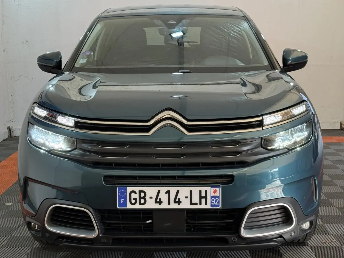 Vue frontale d'un Citroën C5 Aircross Hybrid bleu avec phares LED allumés et calandre distinctive.