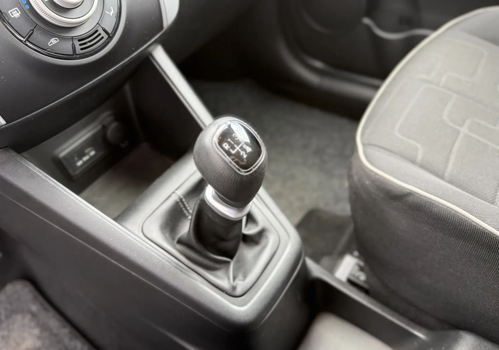 Gros plan sur le levier de vitesses manuel noir et la console centrale d'une Kia Venga 1.4 i 90 Active de 2013.