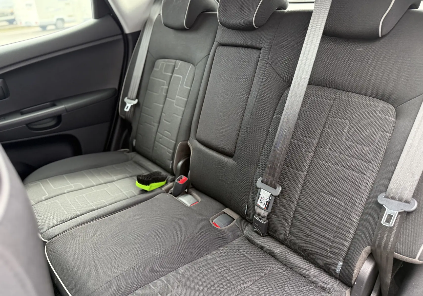 Vue intérieure côté droit des sièges arrière en tissu gris foncé de la Kia Venga 1.4 i 90 Active avec ceinture de sécurité visible.