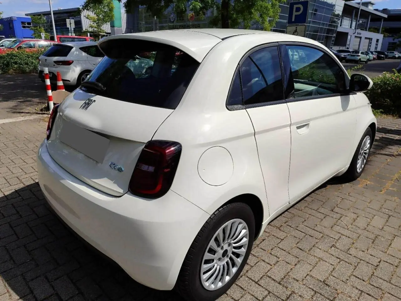 Vue intérieure côté droit de la FIAT 500 électrique 2024, sièges noirs avec surpiqûres blanches et motifs FIAT embossés.