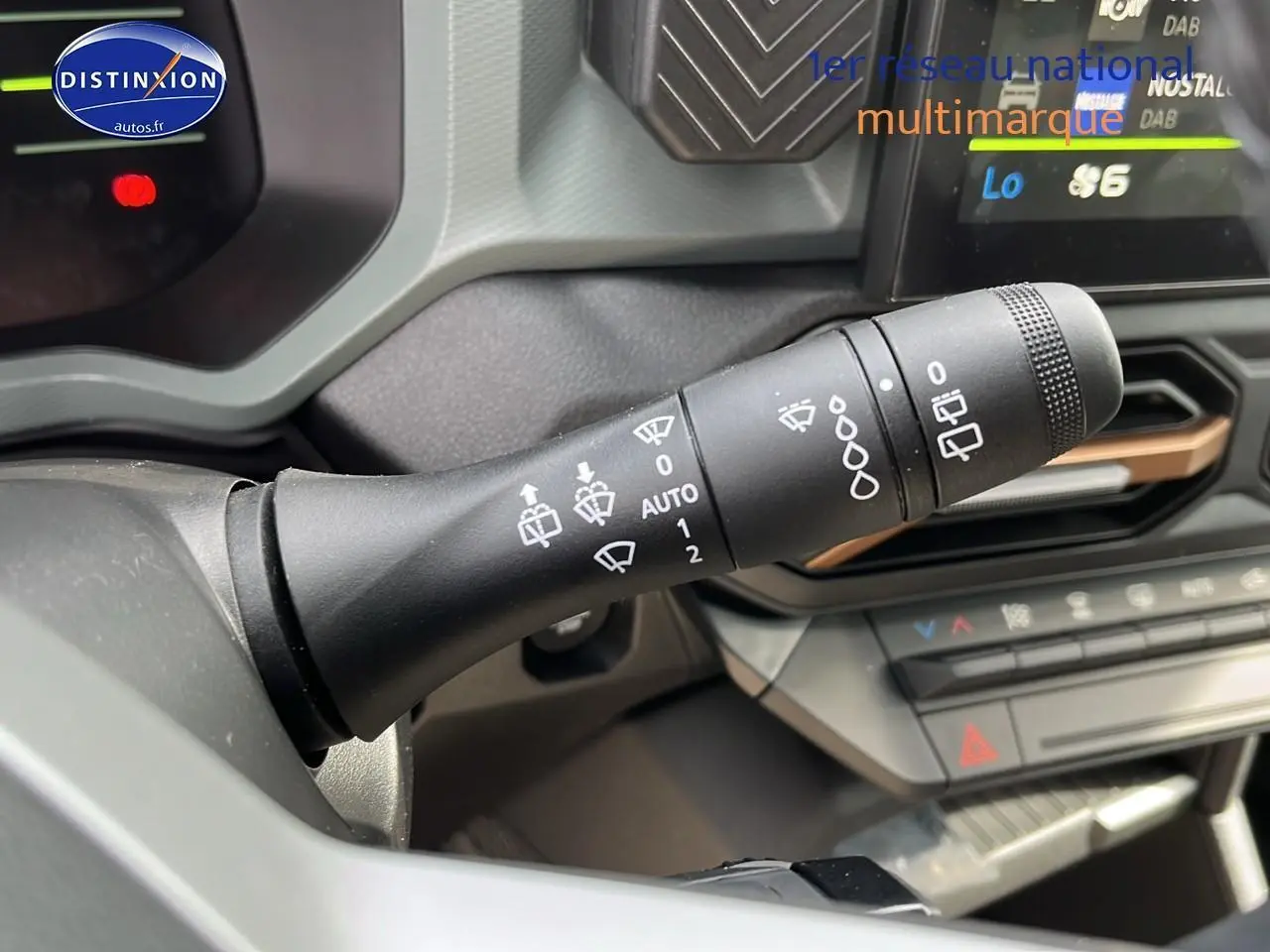 Gros plan sur la commande d’essuie-glace du Dacia Duster 2025 couleur Sandstone, intérieur moderne avec écran tactile.