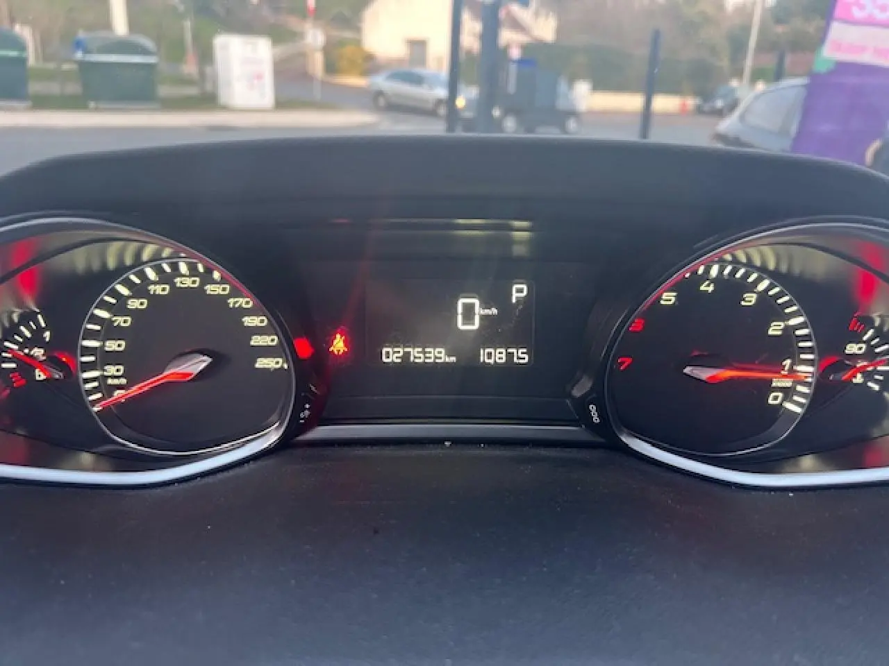 Vue rapprochée du tableau de bord numérique de la Peugeot 308 blanche, affichant 27539 km et indicateurs allumés.