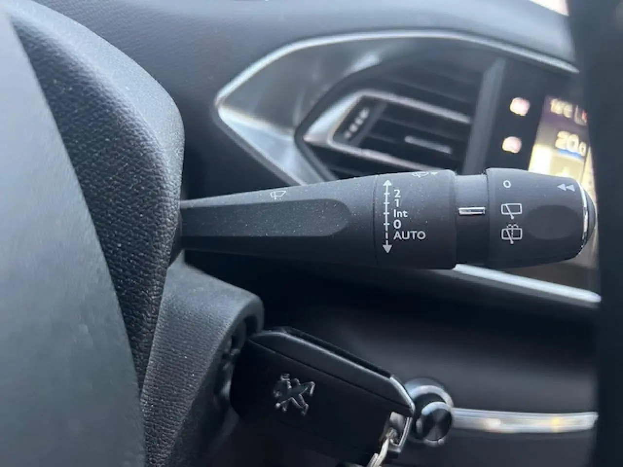 Gros plan sur la commande d'essuie-glace et la clé Peugeot dans l'habitacle de la 308 blanche de 2017.