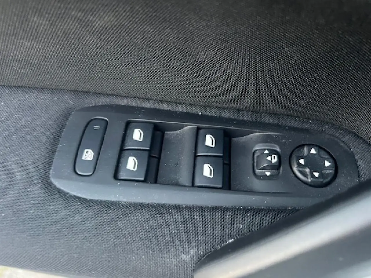 Panneau de commandes des vitres et rétroviseurs sur la porte côté gauche d'une Peugeot 308 blanche de 2017.