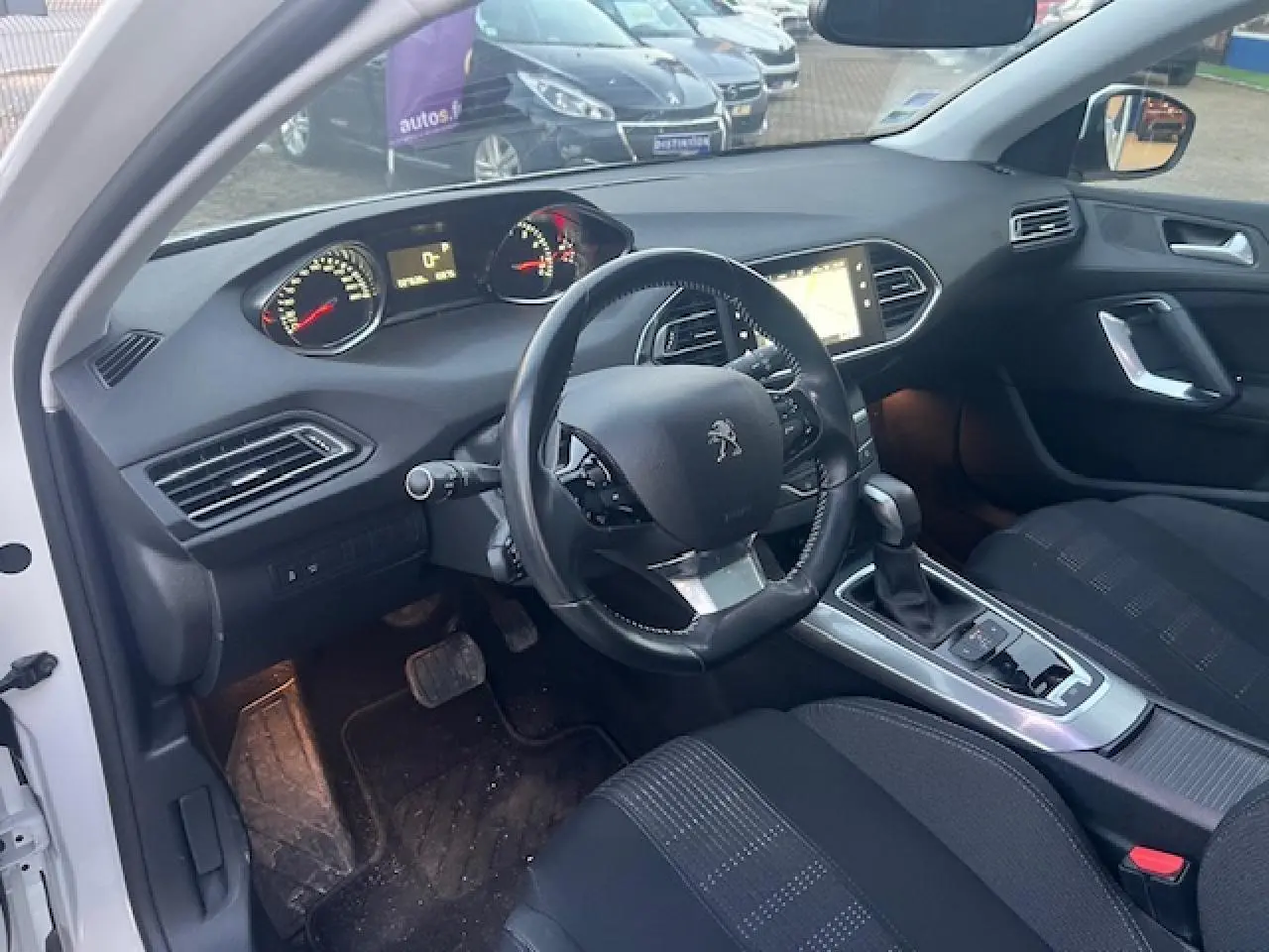 Intérieur de la Peugeot 308 blanc vue côté conducteur, tableau de bord avec écran tactile et volant multifonctions.