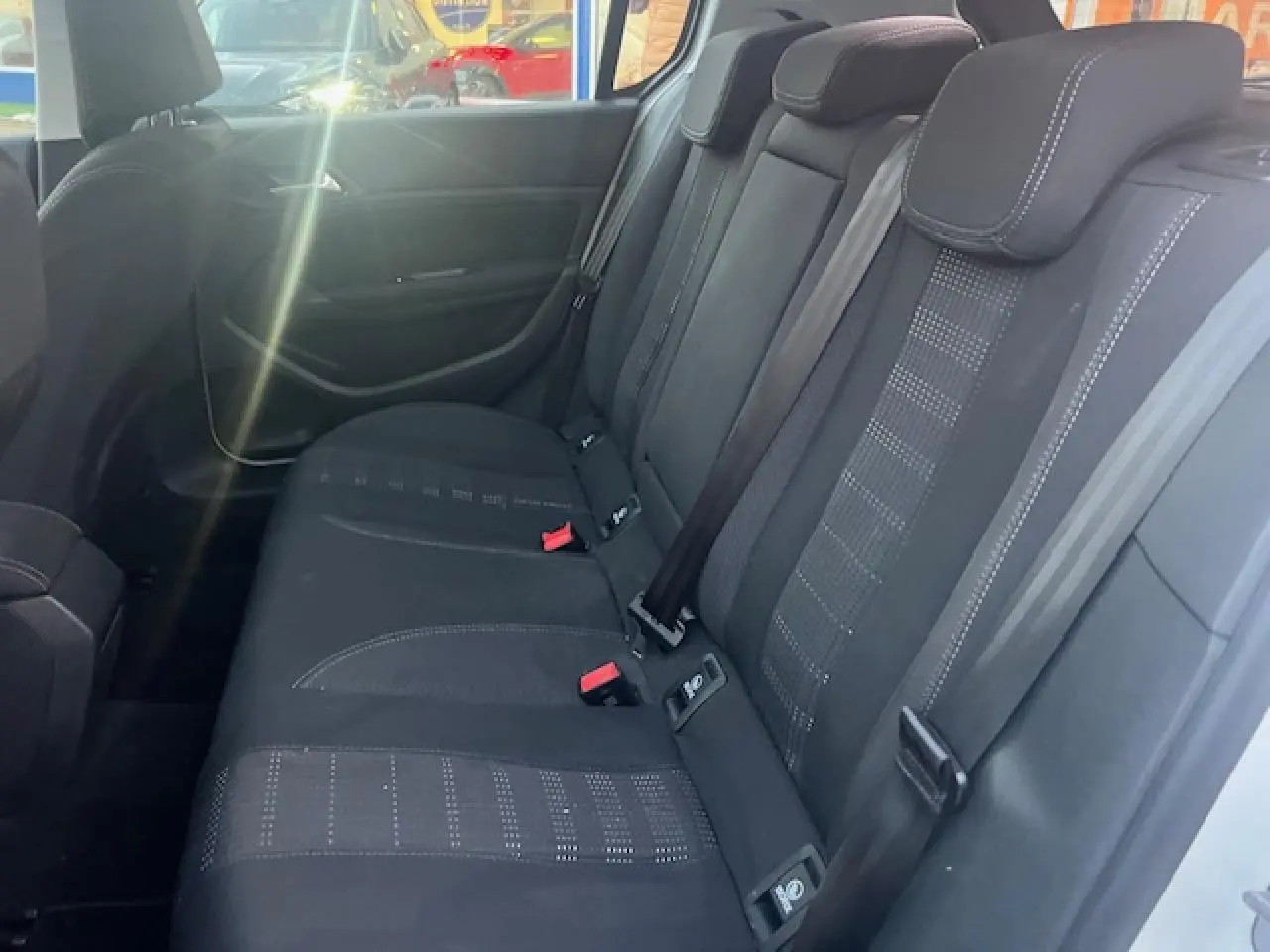 Vue intérieure côté droit montrant la banquette arrière noire avec appuie-têtes et ceintures de sécurité du Peugeot 308 blanc.