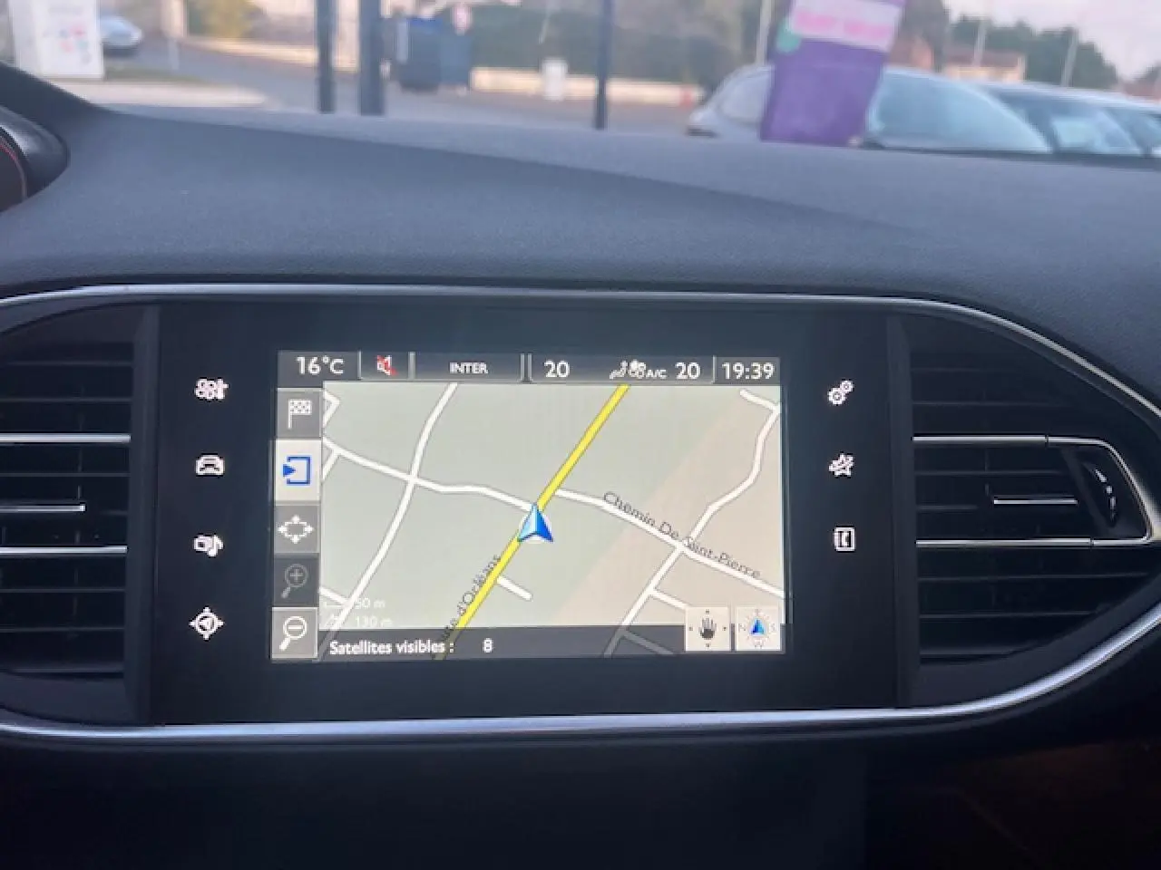 Écran tactile de navigation de la Peugeot 308 blanche, vue intérieure centrée sur la console centrale.