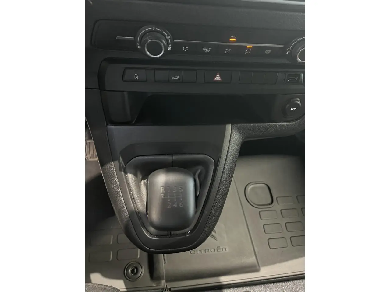 Gros plan sur la boîte manuelle noire et la console centrale du Citroën Jumpy XL blanc, avec tapis de sol marqué Citroën.