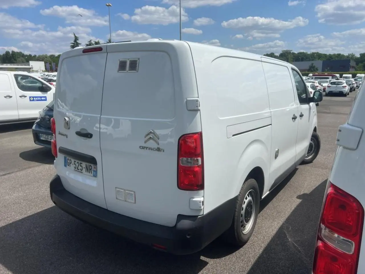 Vue 3/4 arrière droite d'un utilitaire Citroën Jumpy XL blanc avec portes battantes et jantes tôles noires.