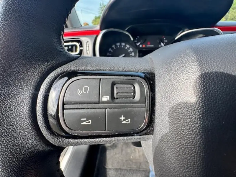 Gros plan sur les commandes audio au volant cuir de la Citroën C3 2017, avec tableau de bord en arrière-plan.