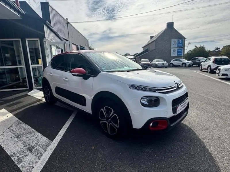 Citroën C3 2017 blanc Banquise avec toit et rétroviseurs rouges, vue 3/4 avant droit en extérieur.