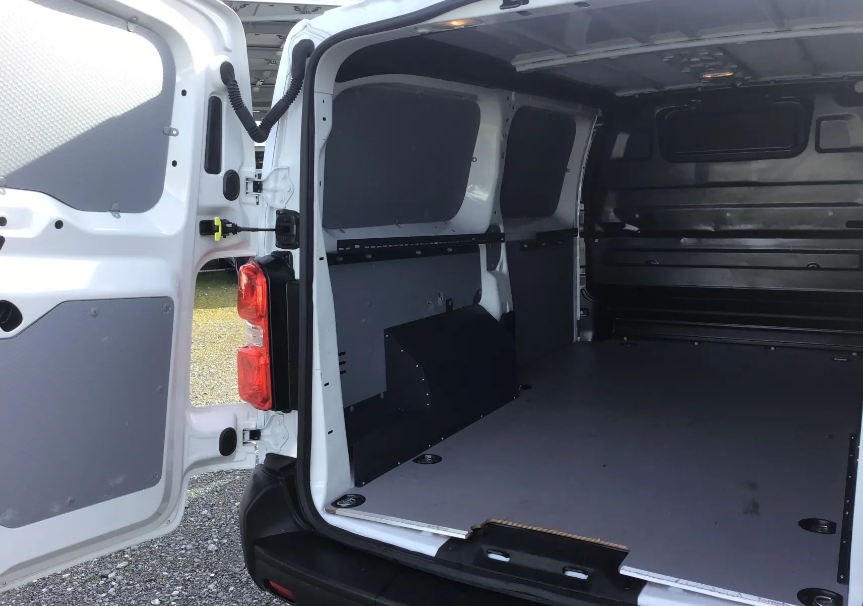 Vue arrière ouverte du FIAT Scudo Fourgon blanc 2024, montrant l’intérieur utilitaire avec protection et cloison noire.