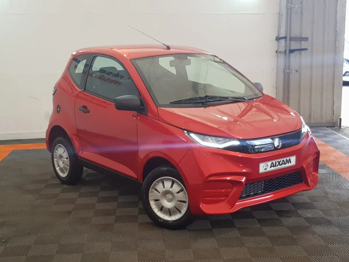 Vue 3/4 avant droite d'une Aixam Ambition 0.5 City Pack rouge avec rétroviseur caméra côté gauche visible.