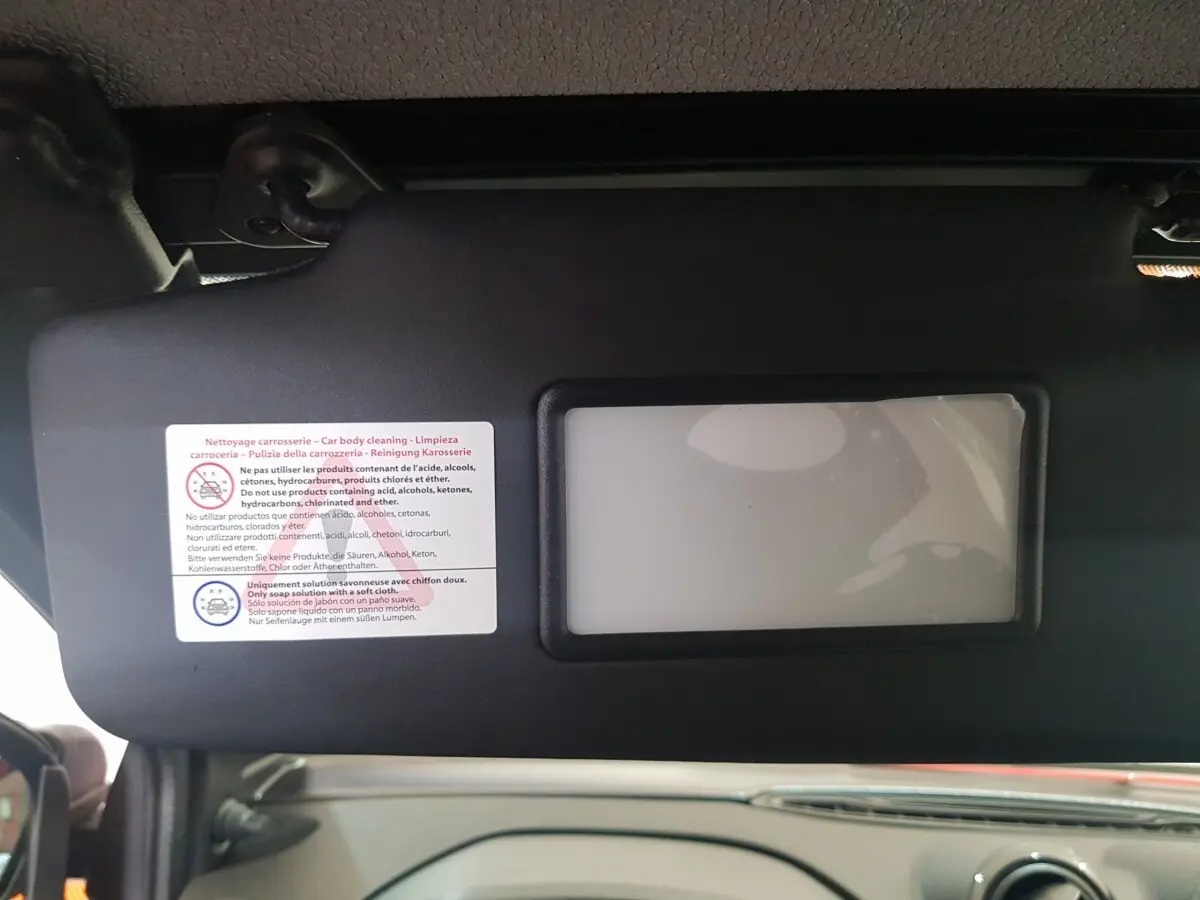 Intérieur de l'AIXAM AMBITION 0.5 CITY PACK 2026, vue sur le pare-soleil avec miroir et consignes de nettoyage.