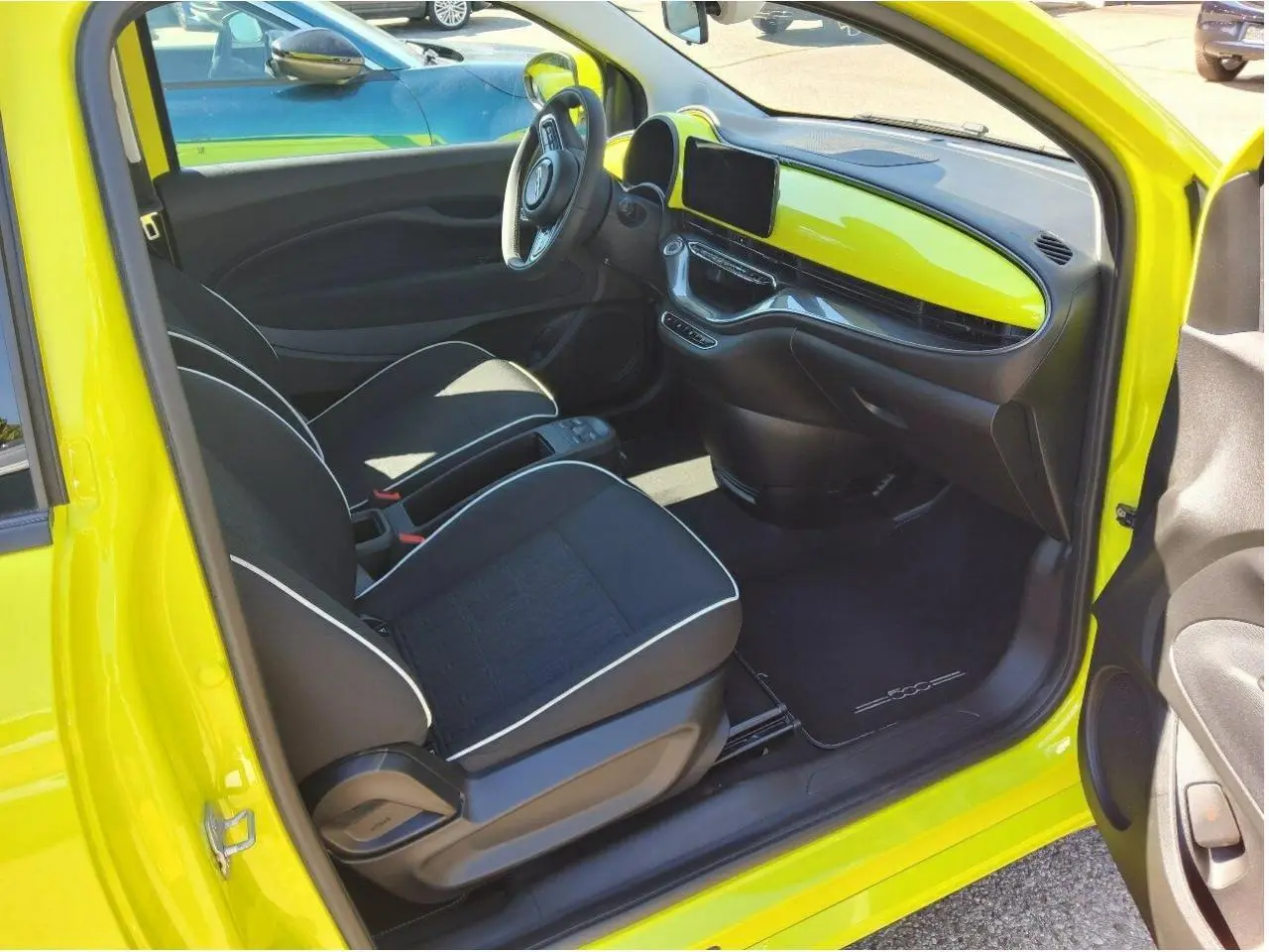 Intérieur de la FIAT 500 électrique jaune Acid, vue côté conducteur avec tableau de bord et sièges noirs.