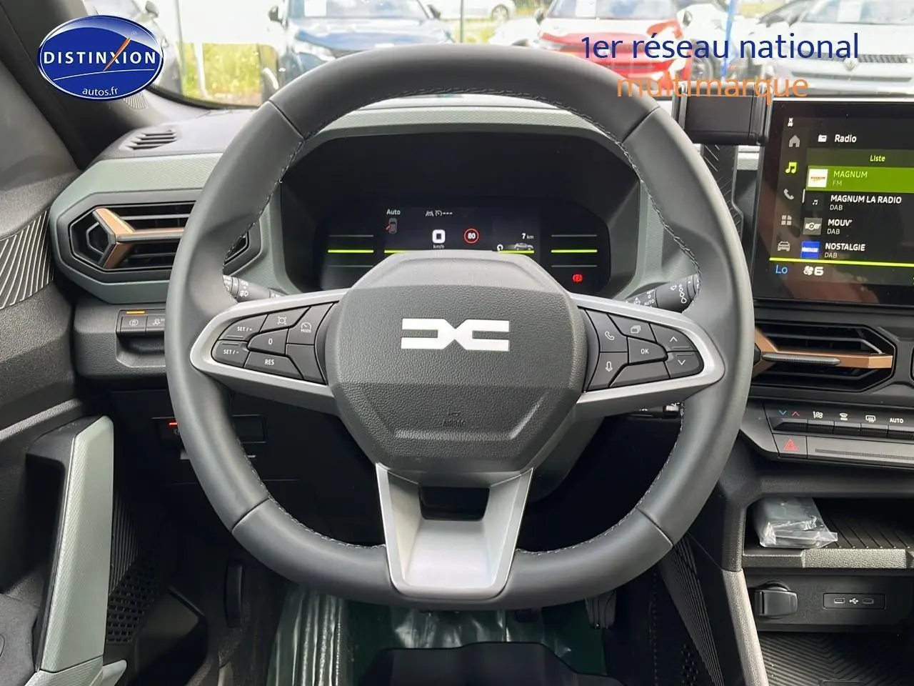 Vue centrée sur le volant multifonction noir et gris du Dacia Duster 2025 avec tableau de bord numérique et écran tactile.