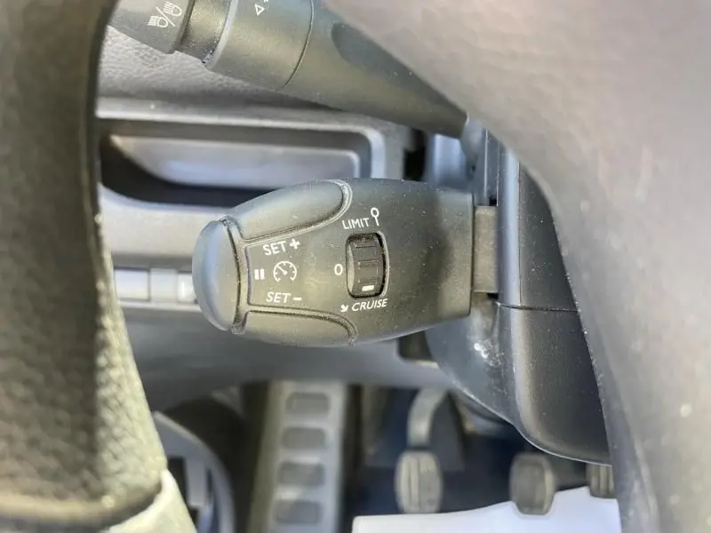 Gros plan sur le levier de régulateur de vitesse noir du Peugeot Expert Fourgon blanc, côté gauche du volant.