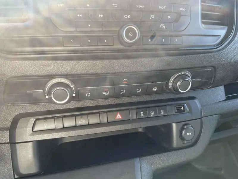 Gros plan sur la console centrale du Peugeot Expert Fourgon blanc 2023, montrant les commandes de climatisation et les boutons fonctionnels.
