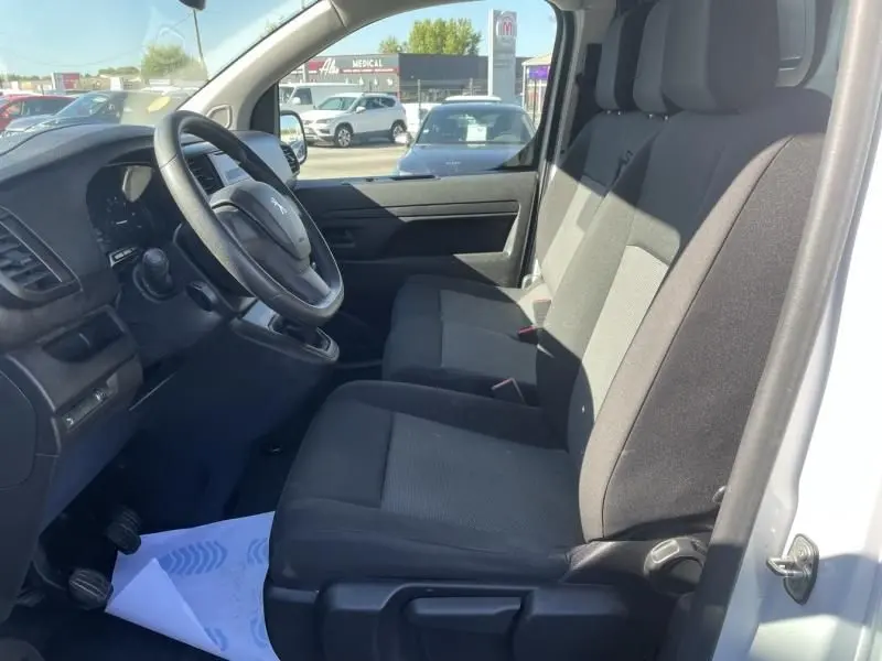 Intérieur avant du Peugeot Expert Fourgon blanc 2023, vue côté conducteur montrant sièges tissu et volant simple.