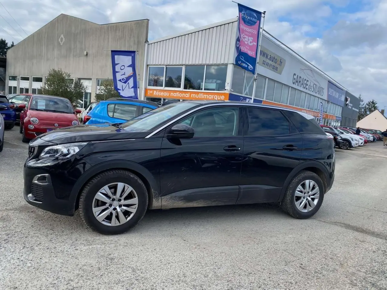 Peugeot 3008 noir vue de profil côté gauche, avec des traces de boue sur les bas de caisse, stationné devant un garage.