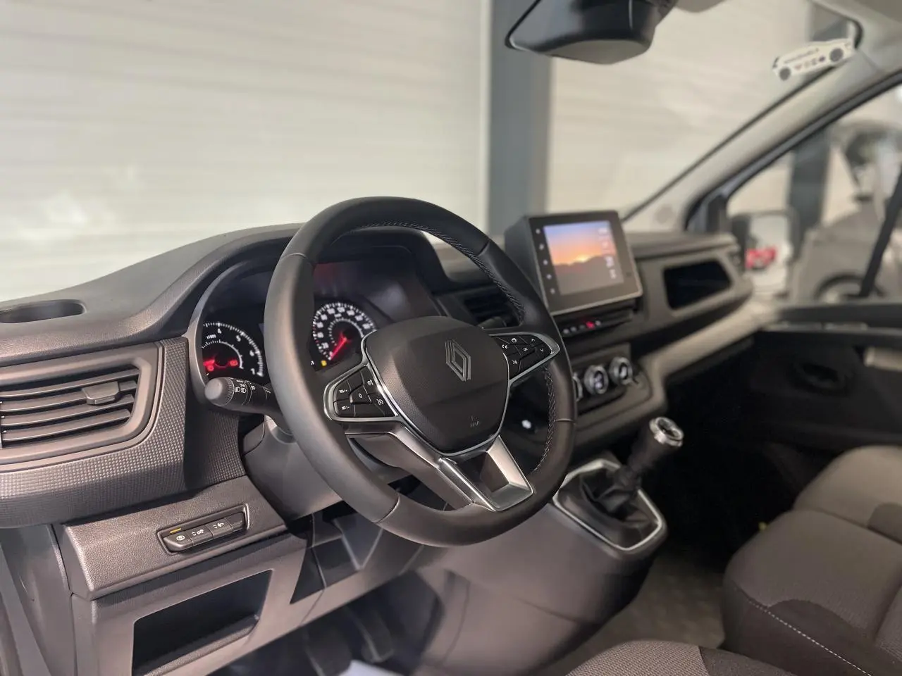 Vue intérieure du poste de conduite du Renault Trafic Fourgon blanc, avec volant multifonction et écran tactile central.