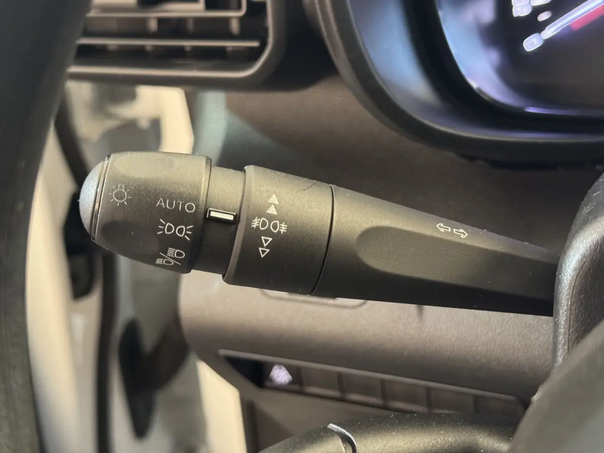 Gros plan sur la manette de commande des phares et clignotants du Citroën Berlingo blanc, vue côté conducteur.