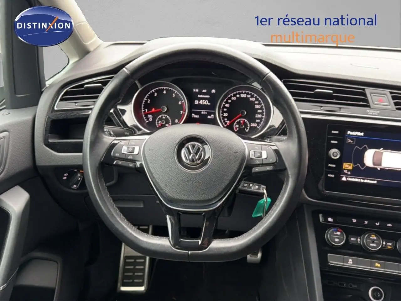 Vue intérieure centrée sur le volant de la Volkswagen Touran 2018 avec tableau de bord et écran tactile visibles.