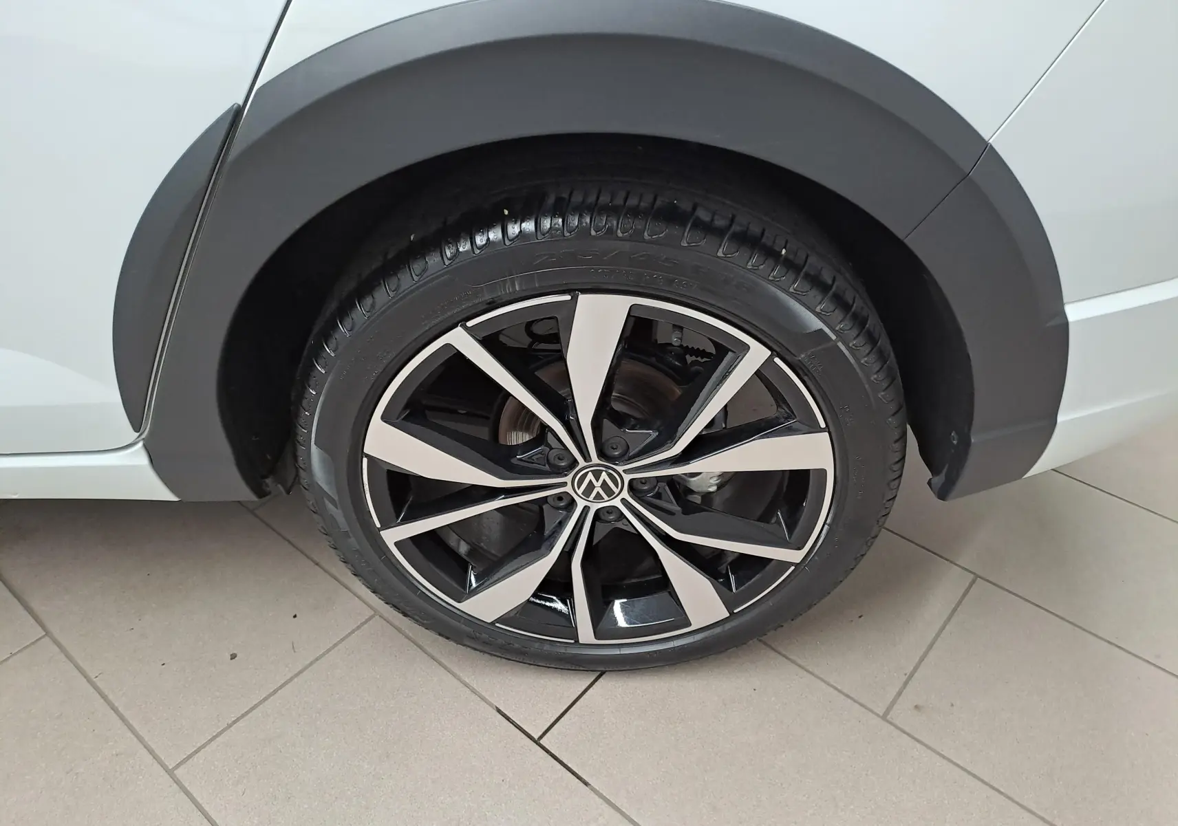 Gros plan sur la jante alliage 18 pouces bicolore du côté arrière droit du Volkswagen Taigo blanc toit noir.