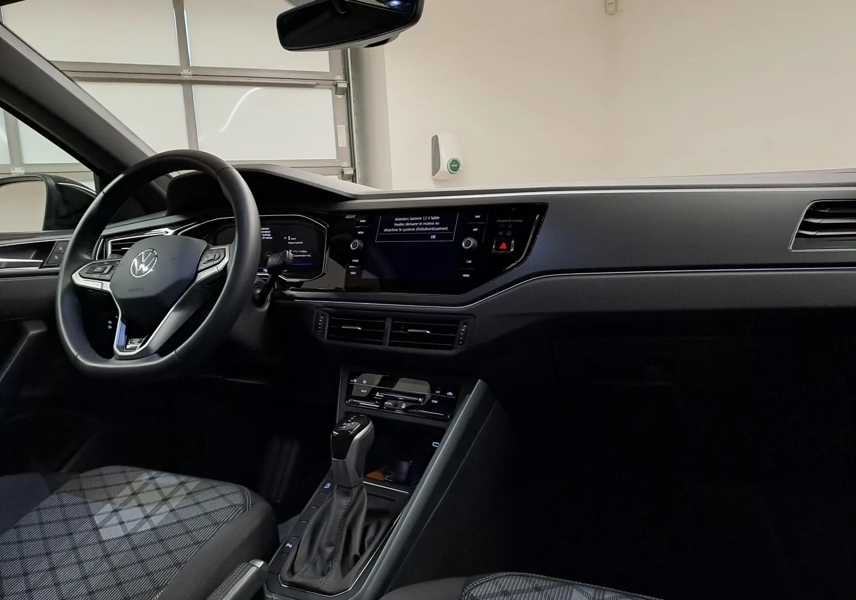 Intérieur avant droit du Volkswagen Taigo 1.5 TSI 150 DSG7 R-Line Edition avec tableau de bord noir et sièges à motif écossais.