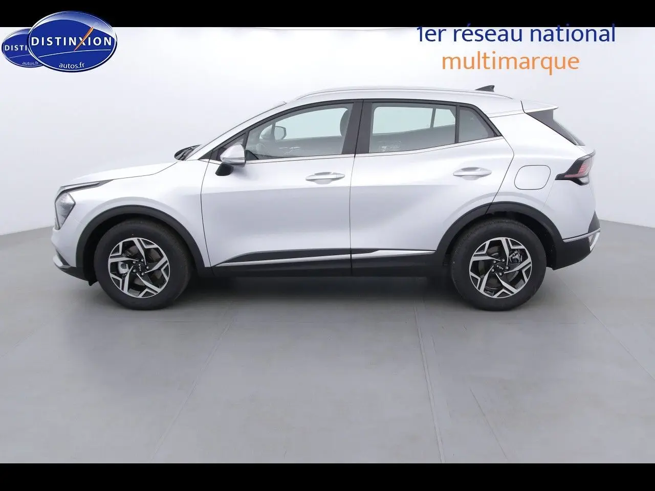 Vue de profil côté gauche du KIA SPORTAGE 2022 gris acier métal avec jantes bicolores et lignes modernes.